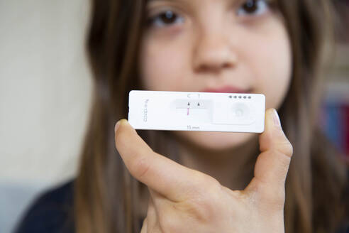 Girl holding rapid diagnostic test at home showing negative result - LVF09164