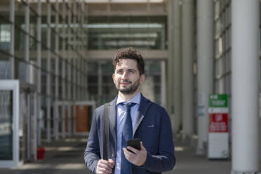 Mittlerer erwachsener männlicher Unternehmer mit Mobiltelefon, der wegschaut - EIF01006