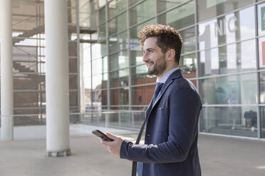 Businessman holding smart phone while looking away - EIF01008