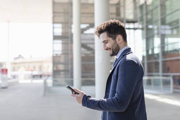 Mid adult male entrepreneur smiling while using mobile phone - EIF01009