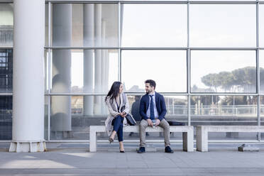 Business couple talking while sitting on bench - EIF01047