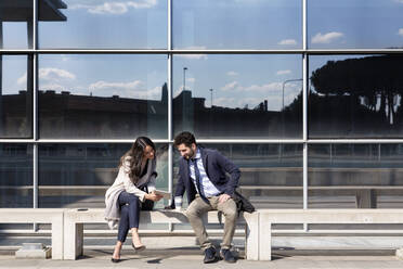 Male and female entrepreneurs discussing over digital tablet on sunny day - EIF01049