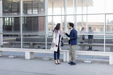 Business couple talking while standing on footpath - EIF01059