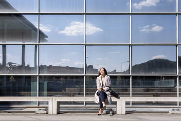 Young businesswoman sitting with eyes closed on bench - EIF01060