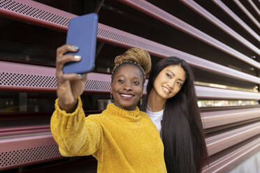 Afrikanische Frau, die ein Selfie mit ihrer Freundin durch ein Smartphone an der Wand macht - JCCMF02230