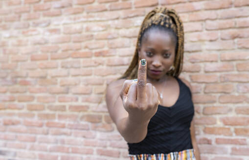Afrikanische Frau zeigt Mittelfinger an der Wand - JCCMF02278