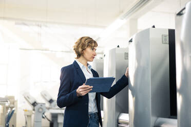 Weiblicher Manager mit digitalem Tablet zur Überprüfung einer Maschine in einer Fabrik - JOSEF04231