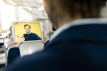 Businessman having discussion with colleague on video call through digital tablet in industry - JOSEF04252