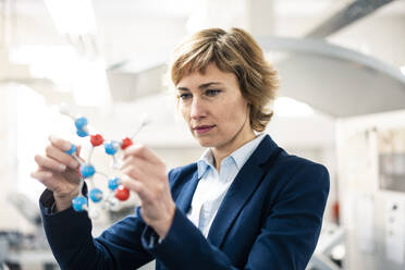 Female engineer holding molecular structure model  in industry - JOSEF04322