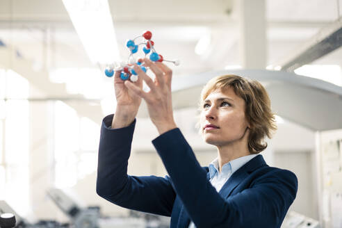 Mature expertise holding molecular structure model at workshop - JOSEF04323