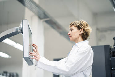 Technician wearing lab coat operating printing machine in laboratory - JOSEF04332