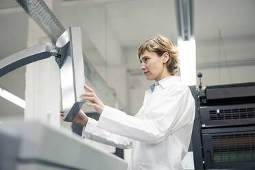 Mature female scientist operating printing machine in laboratory - JOSEF04340