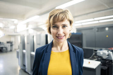 Mature businesswoman smiling in printing industry - JOSEF04356