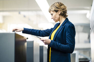 Weibliche Fachkraft mit digitalem Tablet, die eine Maschine in einer Druckerei bedient - JOSEF04358