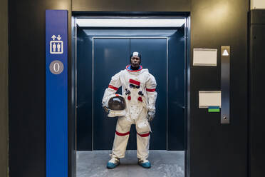 Männlicher Astronaut mit Weltraumhelm steht im Aufzug - MEUF02697