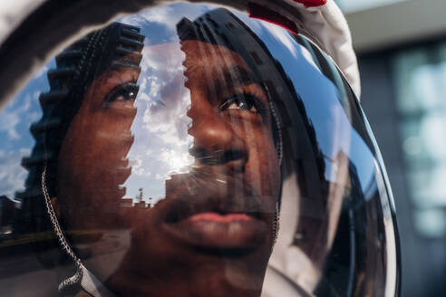 Male astronaut wearing space helmet looking up - MEUF02703