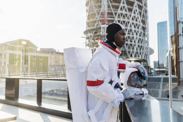 Männlicher Astronaut, der auf einem Dach stehend wegschaut - MEUF02706