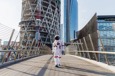 Mittlerer erwachsener Astronaut im Raumanzug auf einer Brücke an einem sonnigen Tag - MEUF02710