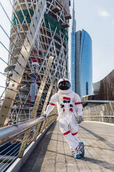 Männlicher Astronaut auf einem Bein stehend auf einer Brücke - MEUF02713