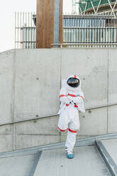 Männlicher Astronaut stehend mit verschränkten Armen an die Wand gelehnt - MEUF02736
