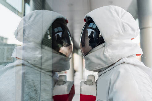 Mittlerer erwachsener Astronaut mit Blick auf eine Glaswand - MEUF02745