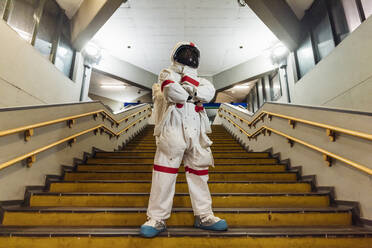 Männlicher Astronaut mit verschränkten Armen auf einer Treppe stehend - MEUF02766