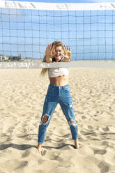 Woman showing hands while playing volleyball on sand during sunny day - OIPF00644