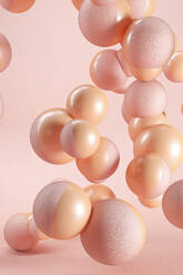 Three dimensional render of pink and orange spheres floating against pink background - JPSF00164