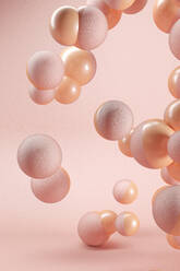 Three dimensional render of pink and orange spheres floating against pink background - JPSF00165