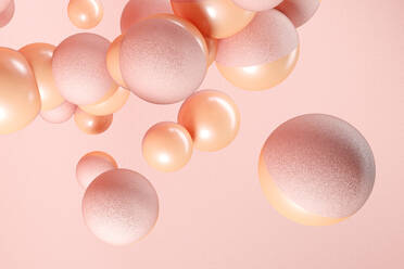 Three dimensional render of pink and orange spheres floating against pink background - JPSF00166