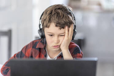 Boy getting bored during online classes attending at home - WPEF04369