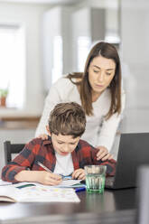 Mother assisting son studying at home - WPEF04382