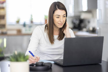 Lächelnde Geschäftsfrau bei der Arbeit zu Hause - WPEF04386