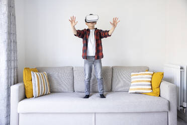 Boy gesturing while using virtual simulator on sofa at home - WPEF04420