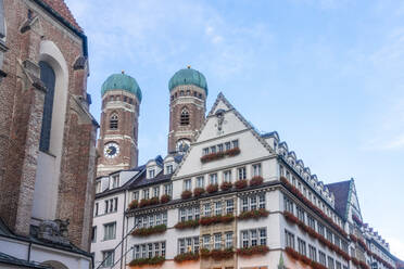 Frauenkirche Zwillingstürme mit kommerziellen historischen Kaufhaus unter Himmel in München, Bayern, Deutschland - TAMF02944