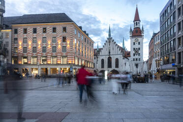 Zufällige Menschen auf dem Fußweg in der Abenddämmerung am Marienplatz mit dem Alten Rathaus von München, Bayern, Deutschland - TAMF02946