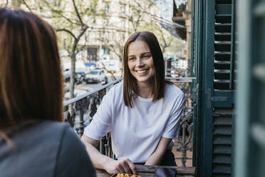 Lächelnde schöne junge Frau verbringt ihre Freizeit mit ihrer Freundin auf dem Balkon - XLGF01750
