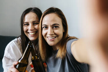 Happy young women taking selfie while toasting beer bottles - XLGF01761