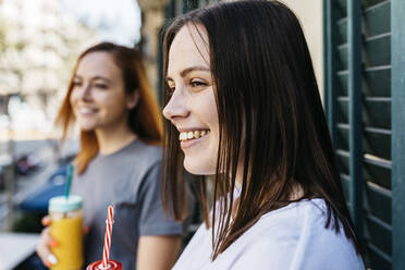 Smiling woman looking away while standing on balcony at home - XLGF01764