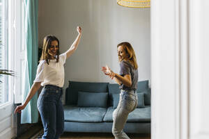 Glückliche Freundinnen tanzen im Wohnzimmer zu Hause - XLGF01770