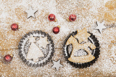 Christmas ornaments and fresh homemade cookies lying on wooden surface - GWF06998