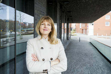 Woman with arms crossed standing at footpath - IHF00445