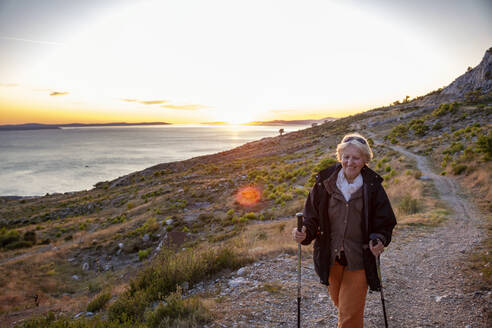 Lächelnde ältere Frau beim Wandern in der Nähe des Adriatischen Meeres in Omis, Dalmatien, Kroatien - MAMF01767