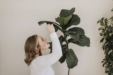 Schwangere Frau begutachtet Pflanze an der Hauswand - SMSF00540