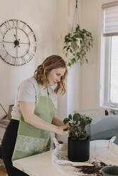 Pregnant woman removing dirt from potted plant at home - SMSF00553