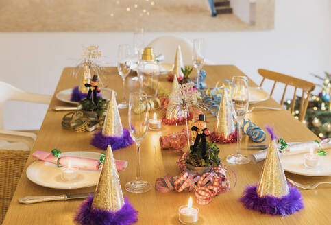 Festlich gedeckter Silvestertisch mit Tellern, Kerzen, Partyhüten, Sektflöten und Schornsteinfegerfiguren - GWF07001