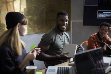 Happy businessman with coworkers discussing during meeting at creative office - MASF23091