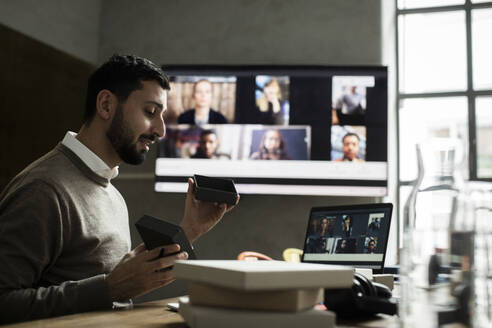 Männlicher Unternehmer, der Kunden per Videokonferenz am Laptop im Büro etwas über sein Produkt erklärt - MASF23122