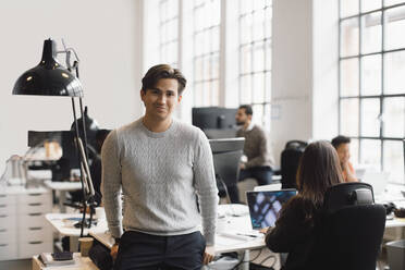 Portrait of male entrepreneur leaning on desk in office - MASF23162