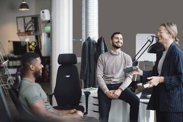 Weibliche und männliche Kollegen lachen, während sie in einem Kreativbüro über ein Produkt diskutieren - MASF23182